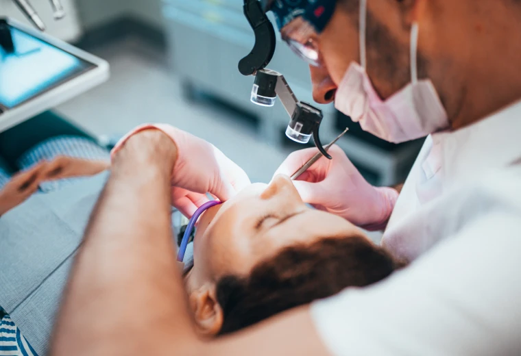 Dentiste utilisant un microscope opératoire pour accéder aux canaux radiculaires d'une dent