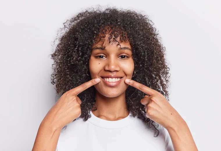 Femme souriante montrant ses dents naturelles préservées après chirurgie endodontique